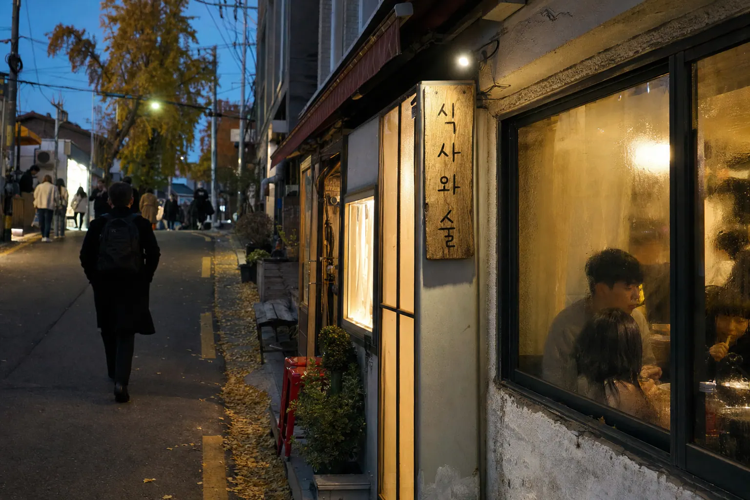 A photorealistic documentary photograph of a narrow Itaewon side street at dusk in autumn, a modest ground-floor restaurant with warm interior lights, a hand-lettered sign, condensation on the glass, a few passersby in coats, no visible brand logos.